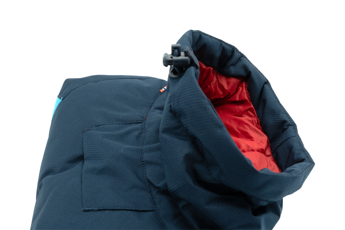 Detailfoto van de opgevouwen Glacier 2.0 winterjas, met focus op de kol, buitenkant is blauw, binnenkant is rood.