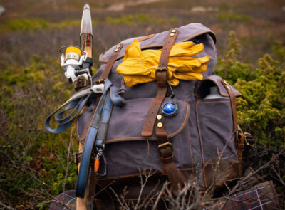 Jeans-look rugzak met diverse materialen en blauwe Orbiloc Carabiner, in een veld