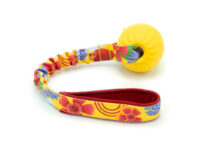 Productfoto van het Jazzy speeltje met bal van Zayma Craft. Handvat in een zomers bloempjesmotief met een gele bal.