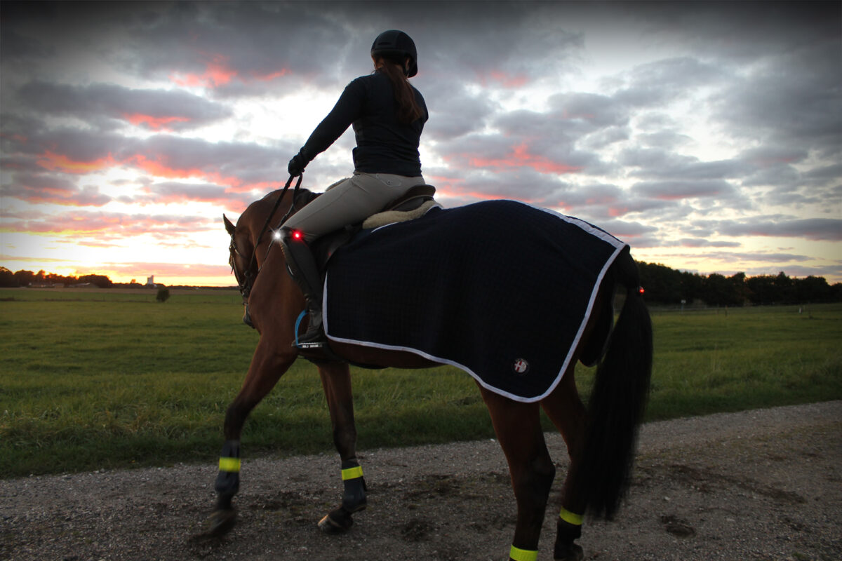 Amazone in schemering op straat met Orbiloc Safety light en clip voor veilig paardrijden in het donker.