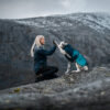 Vrouw en dalmatiër geven elkaar een high-five op een bergtop. De hond draagt de navy glacier 2.0 winterjas.