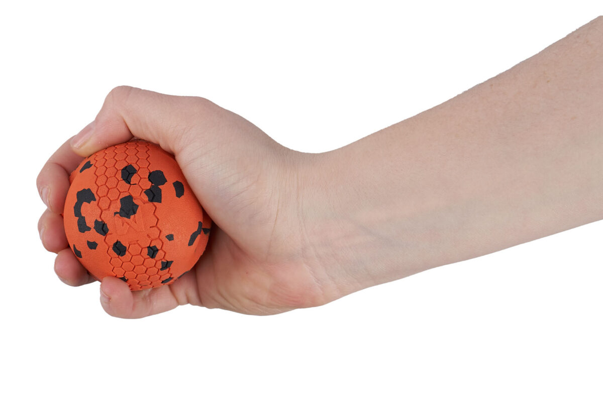 Een mensenhand houdt de oranje Non-stop dogwear bal van 60x60mm vast