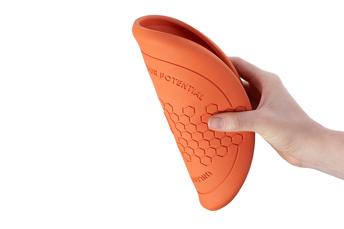 Een hand vouwt de flexibele Flying Disk frisbee voor honden dubbel.