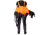 Een mens draagt een hond in een oranje EHBO draagzak van Non-stop dogwear..